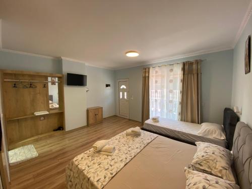 een grote kamer met 2 bedden en een televisie bij Kriss-Klej's Rooms in Sarandë