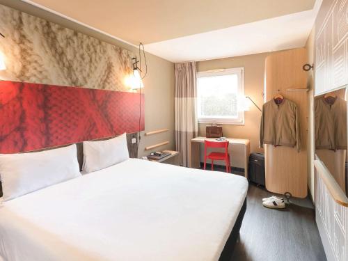 フエンラブラダにあるIbis Madrid Fuenlabradaの白いベッドと赤い壁が備わるホテルルームです。