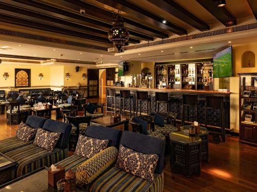 Mercure Grand Hotel Seef - All Suites في المنامة: مطعم فيه كنب وبار في الخلف