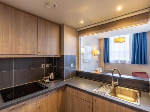 uma cozinha com armários de madeira, um lavatório e uma janela em Aparthotel Adagio Liverpool City Centre em Liverpool