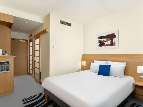 a bedroom with a large white bed and a kitchen at Novotel Budapest Danube in Budapest