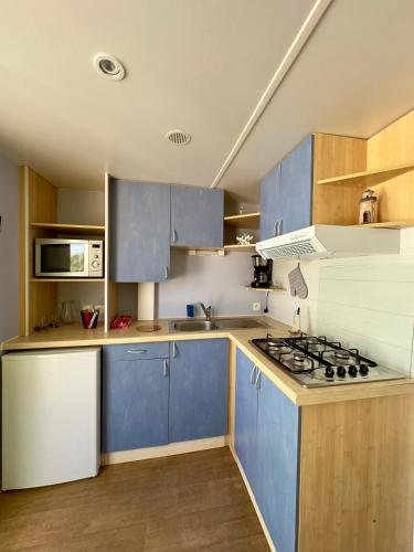 a kitchen with blue cabinets and a stove at Bungalows Camp in Guia