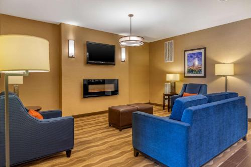a hotel room with blue chairs and a flat screen tv at Comfort Suites San Antonio North - Stone Oak in San Antonio