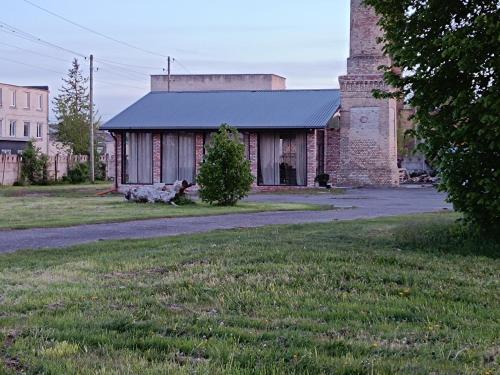 an old brick building with a tower in a field at Templis in Jelgava