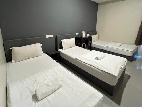 two beds in a room with white sheets at Gebeng Industrial Park Budget Hotel in Kuantan