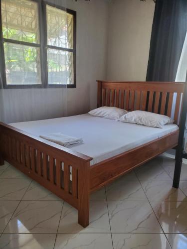 a large wooden bed in a room with two windows at The Nest Haven Hostel in Dar es Salaam
