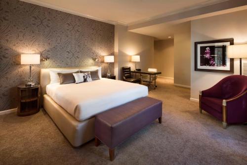 サンノゼにあるHotel De Anza, a Destination by Hyatt Hotelのベッドと椅子付きのホテルルーム