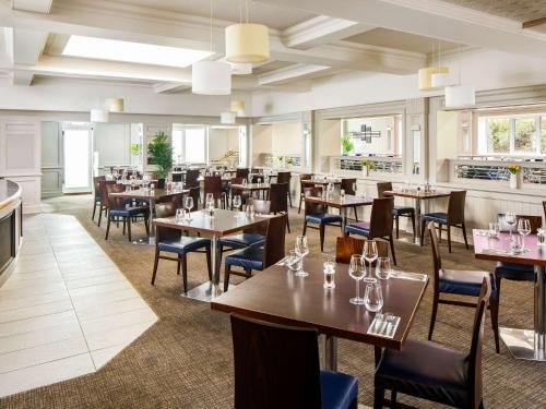 una sala da pranzo con tavoli, sedie e finestre di Mercure Birmingham West Hotel a West Bromwich