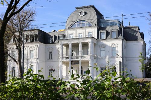 a white house with a dome on top of it at Mirage Medic Hotel in Budapest