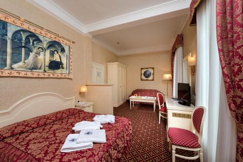 アーバノ・テルメにあるホテル テルメ ローマのベッド2台とデスクが備わるホテルルームです。