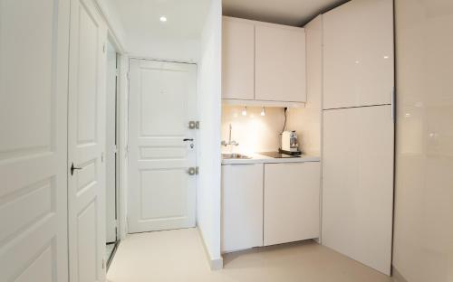 une cuisine blanche avec des placards blancs et une porte dans l'établissement Saint Tropez, coeur de village, appartement unique, à Saint-Tropez