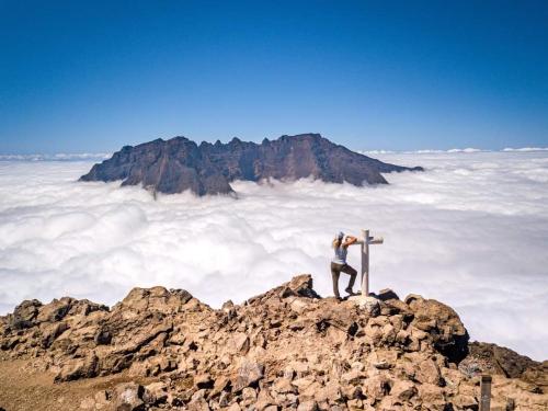 a person standing on top of a mountain with a cross at Villa la fournaise in Le Tampon