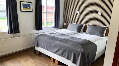 sypialnia z dużym łóżkiem z szarą pościelą w obiekcie Skipalaekur Guesthouse w mieście Egilsstaðir