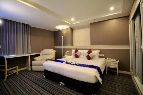 um quarto de hotel com uma cama e uma cadeira em โรงแรมวีวิช V Wish Hotel em Khon Kaen