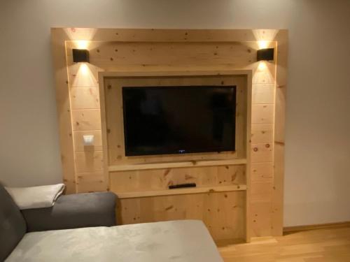 a living room with a tv in a wooden wall at Alpenfarm Poschhof in Kaunerberg