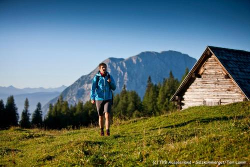 een vrouw die op een grasheuvel naast een hut loopt bij Leben!Pur - Alpenlofts in Bad Mitterndorf