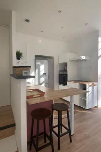 - une cuisine avec une table en bois et deux tabourets de bar dans l'établissement Magnifique duplex avec jardin, à Rivière-Saas-et-Gourby