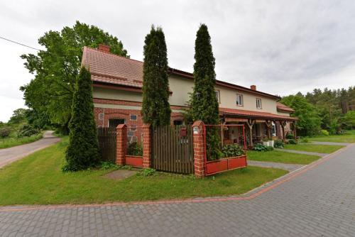a house with a fence and trees on a street at Agropensjonat Stręgielek in Stręgielek