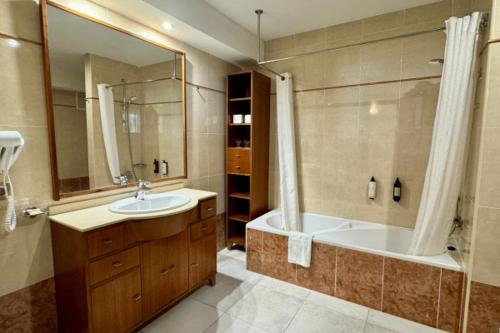 a bathroom with a tub and a sink and a bath tub at Cabot Pollensa Park Spa in Port de Pollensa