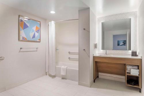 a bathroom with a sink and a tub and a mirror at Comfort Suites Gatlinburg Downtown-Convention Center in Gatlinburg