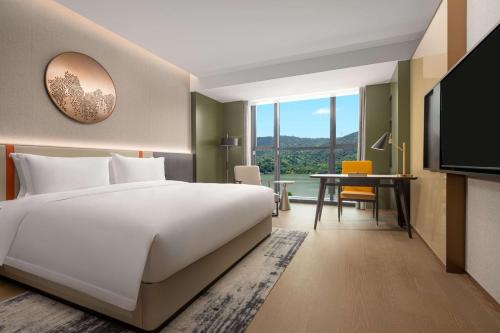台州市にあるWyndham Taizhou Westの大きなベッドとデスクが備わるホテルルームです。