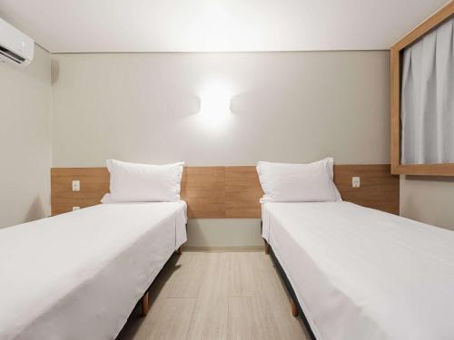two beds in a small room with a window at ibis Styles Goiânia Shopping Estação in Goiânia