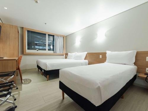 a hotel room with two beds and a window at ibis Styles Goiânia Shopping Estação in Goiânia
