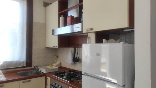 La cuisine est équipée d'un réfrigérateur blanc et d'un évier. dans l'établissement Donatellaguesthouse, à Piove di Sacco