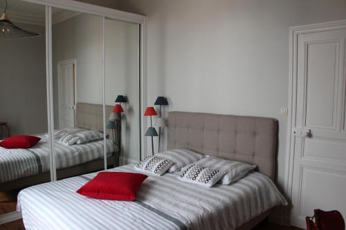 1 dormitorio con 2 camas con almohadas rojas y espejo en le luxe à 2 pas de la grande plage en Les Sables-dʼOlonne