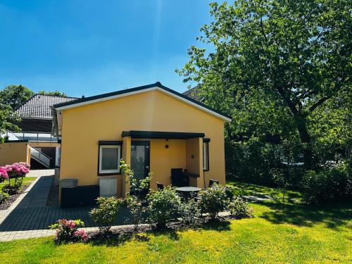 uma pequena casa amarela com um jardim de relva em Bungalow-Wohnung nahe Flughafen Hamburg em Norderstedt