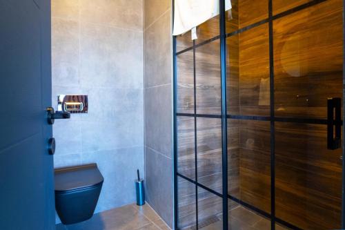 La salle de bains est pourvue de toilettes et d'une porte de douche en verre. dans l'établissement TİRİLYE BALIK OTEL, à Eskipazar