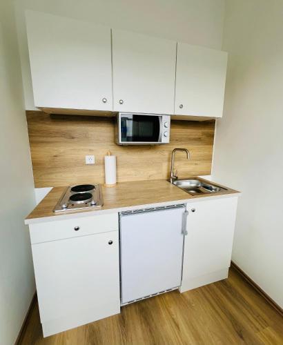 a small kitchen with white cabinets and a microwave at Zentral gelegenes und stilvoll möbliertes Apartment in Duisburg Nur 5 Minuten vom Hbf und City, ideal für Pendler und Messebesucher in Duisburg
