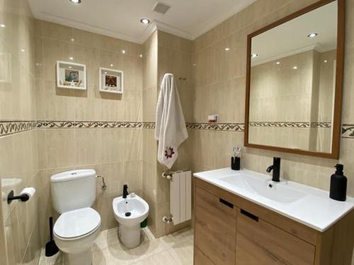 a bathroom with a toilet and a sink and a mirror at Bajo con Jardin y Piscina! in Galizano