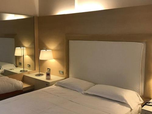 a bedroom with a white bed and a mirror at Smy Bologna Centrale in Bologna