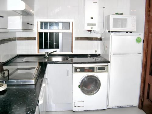een witte keuken met een wasmachine en een wastafel bij 3 bedrooms house with enclosed garden and wifi at Rada in Mélida