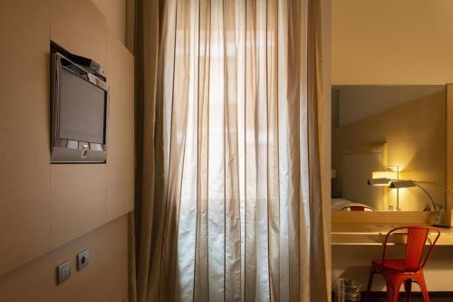 a room with a curtain and a television on a wall at Smy Bologna Centrale in Bologna