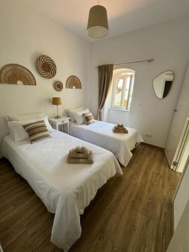 two beds in a room with white walls and wood floors at Casa Nova Vida in Paderne