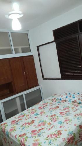 a bedroom with a bed with a flowered blanket at Conceitual Hostel Natal in Natal