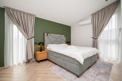 a bedroom with a bed and green walls and windows at SeaView, 5*Appartment,RoofTopTerrace, WalkToBeach in Šventoji