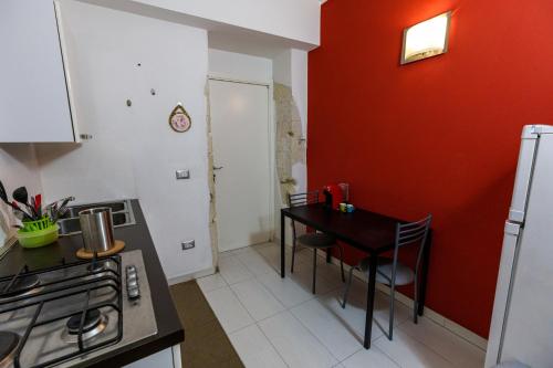 eine Küche mit einem Tisch und einer roten Wand in der Unterkunft Onlyrooms II - Old Town & Typical Food in Cagliari