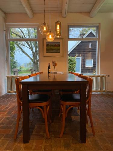 a dining room with a wooden table and chairs at Bed & breakfast De Loeghoeve in Anderen