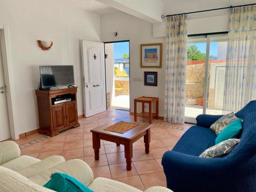 a living room with a blue couch and a tv at Villa Cristipaulo in Praia de Faro