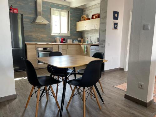 una cucina con un tavolo di legno e sedie nere di Villa Cristipaulo a Praia de Faro