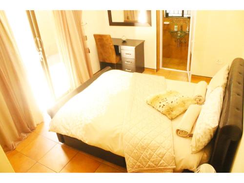 Schlafzimmer mit einem Bett mit weißer Bettwäsche und Handtüchern in der Unterkunft Peace at Home in Augustinium