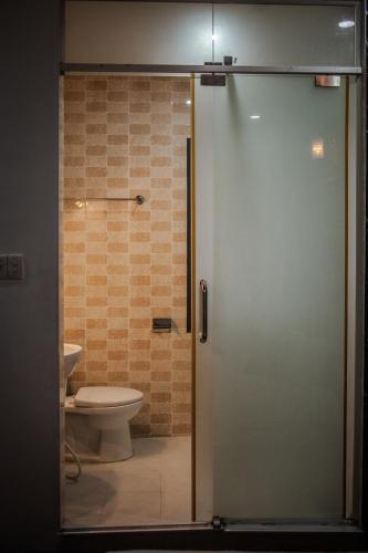 a bathroom with a toilet and a glass shower door at Saigon Hub Hostel in Ho Chi Minh City