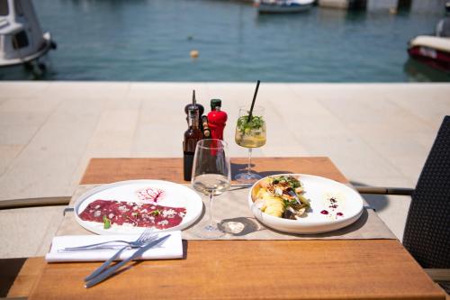 a table with two plates of food and wine glasses at Hotel Marina in Fažana