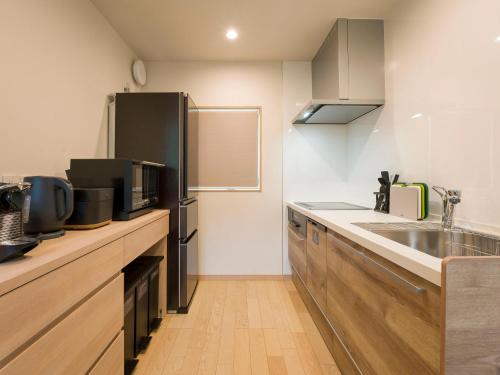 a kitchen with a sink and a black refrigerator at Rakuten STAY VILLA Kinugawa Riverside in Nikko