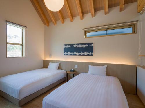 two beds in a room with two windows at Rakuten STAY VILLA Kinugawa Riverside in Nikko