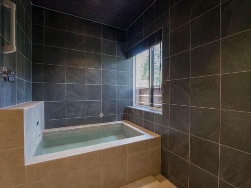 a bathroom with a tub and a window at Rakuten STAY VILLA Kinugawa Riverside in Nikko