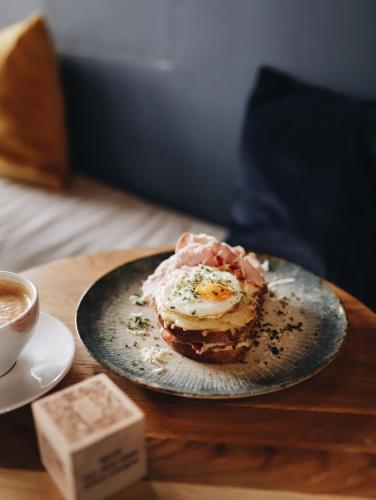 a plate with an egg on a table with a cup of coffee at Kolejowa ApartHotel in Warsaw